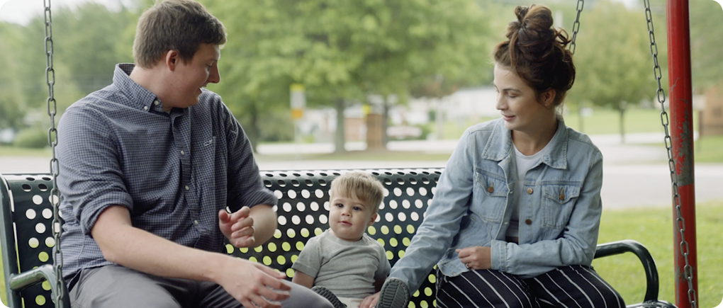 Parents with toddler on bench swing in daytime