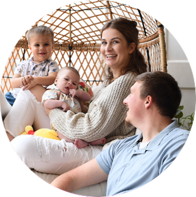 Parents with young boy and baby all smiling in a swinging chair